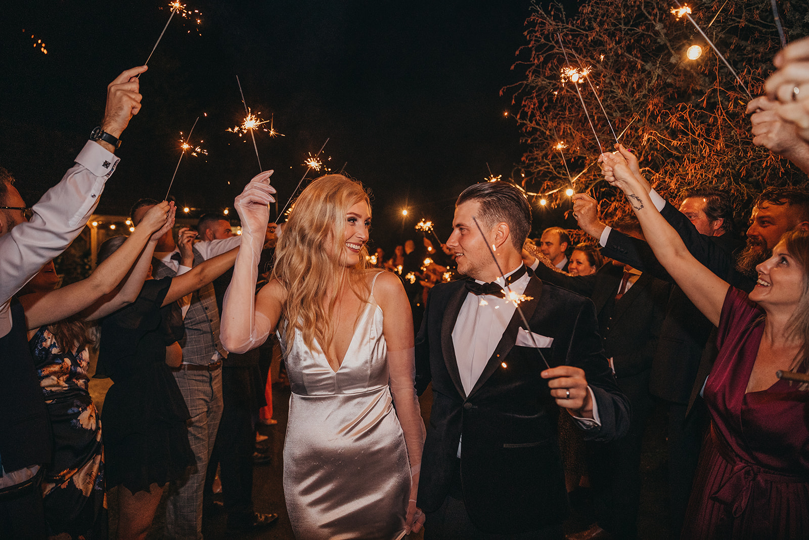 Bride and groom walking through a tunnel of their guests holding sparklers