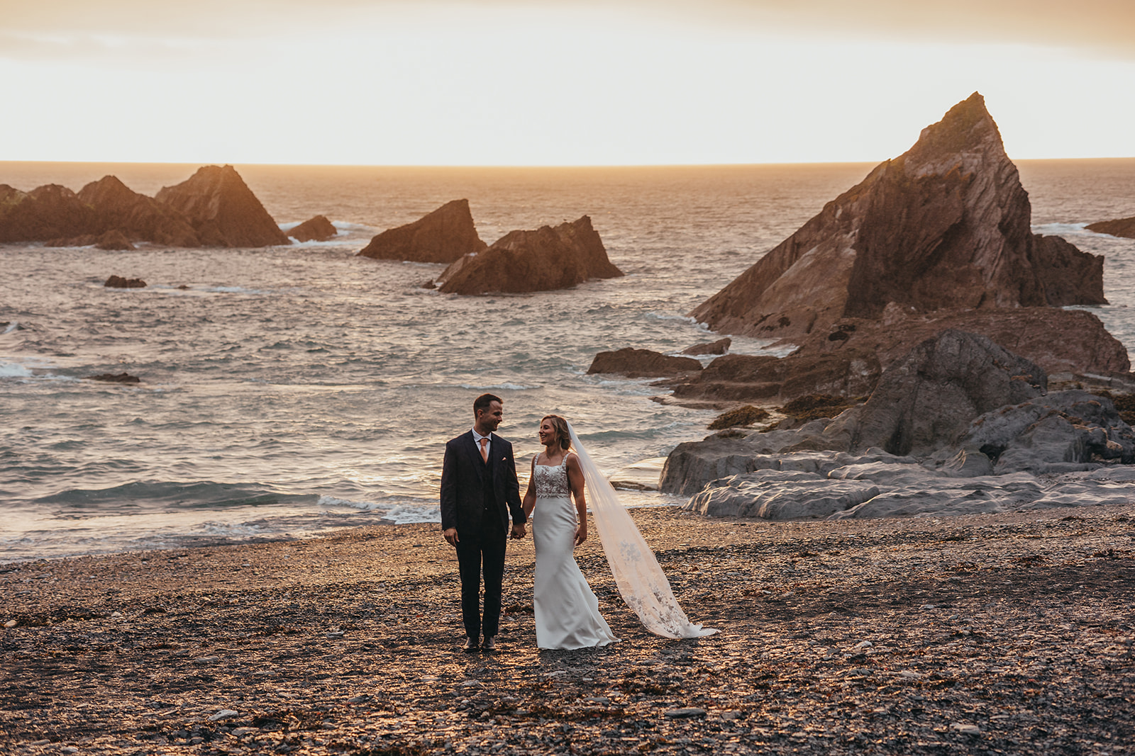 Bride and groom on at Tunnels `beaches during sunset